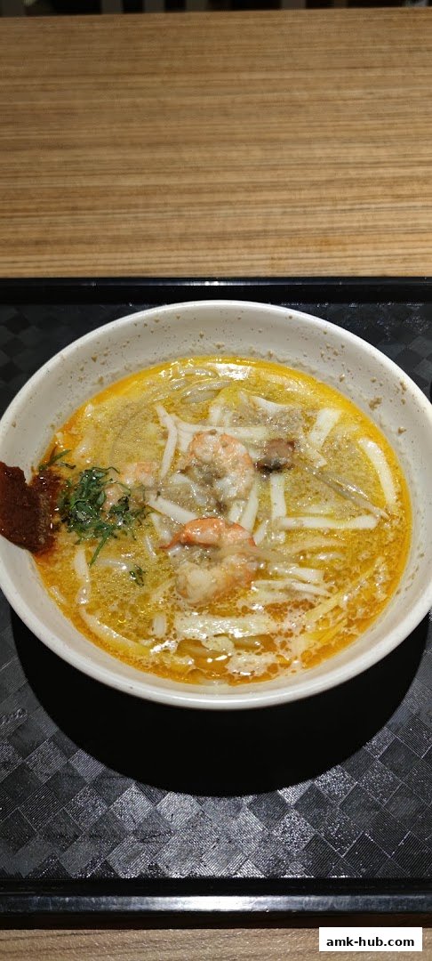A close-up shot of a delicious bowl of Laksa with shrimp and noodles.