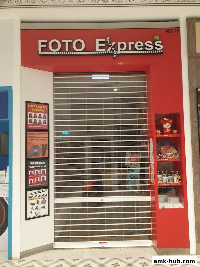 The exterior of a Foto Express shop with its shutter down and promotional posters visible.