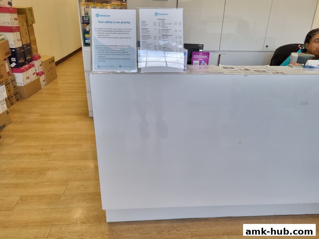 A reception desk at Denticare with informational posters and a staff member.