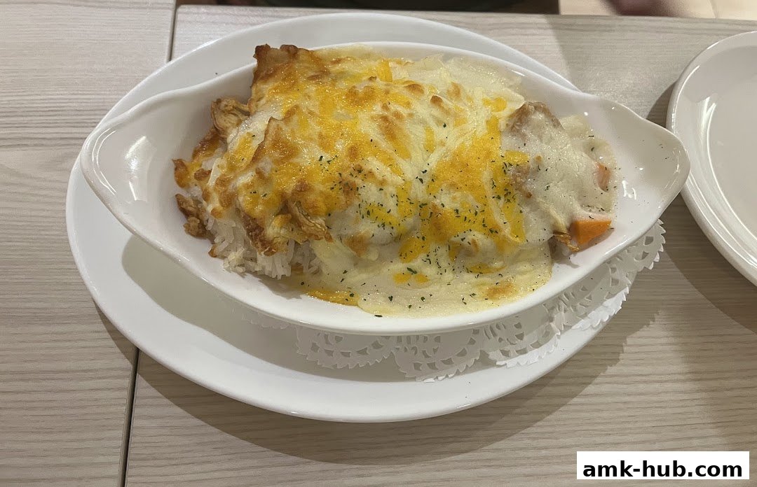 A close-up of a cheesy baked rice dish with chicken and vegetables.
