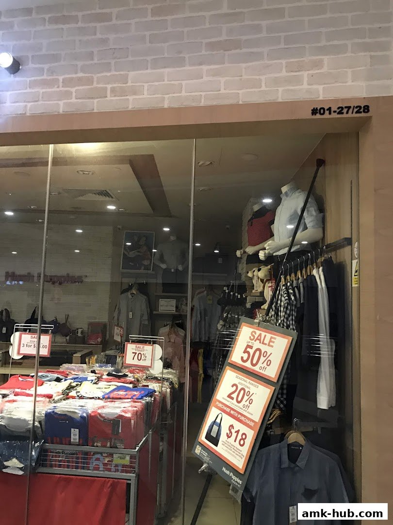 Hush Puppies store window displaying sale signs and clothing on mannequins and racks.
