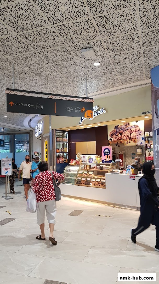 Famous Amos cookie shop with a display of cookies and people walking by.