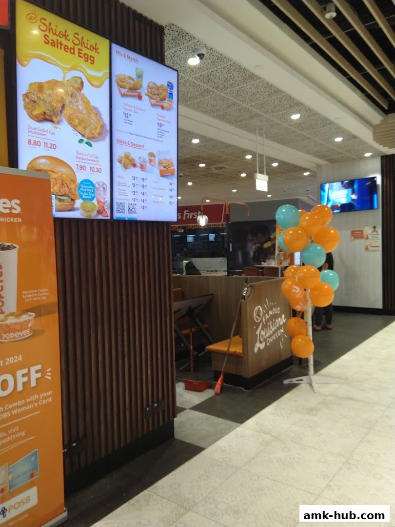 A Popeyes restaurant interior with digital menus displaying food and prices, and balloons.