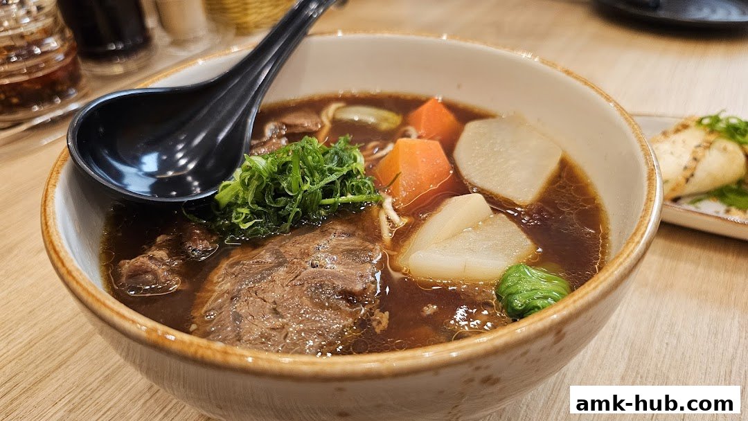 A close-up of a steaming bowl of beef noodle soup with tender beef, carrots, and daikon radish.
