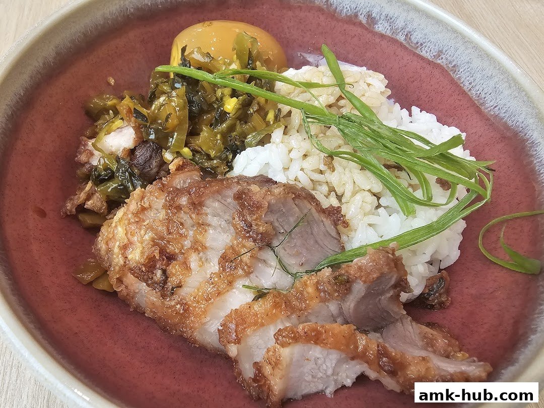 A close-up of a delicious meal featuring crispy pork, rice, and pickled vegetables.