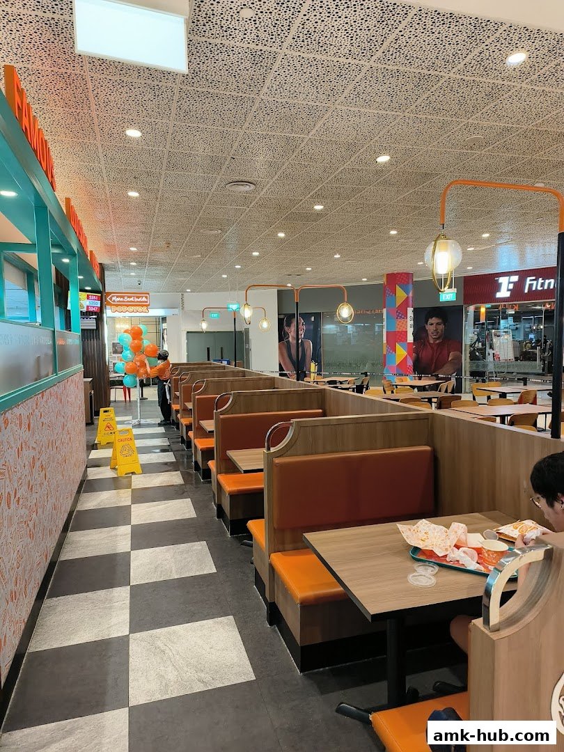Interior view of Popeyes restaurant with seating booths and a person eating.