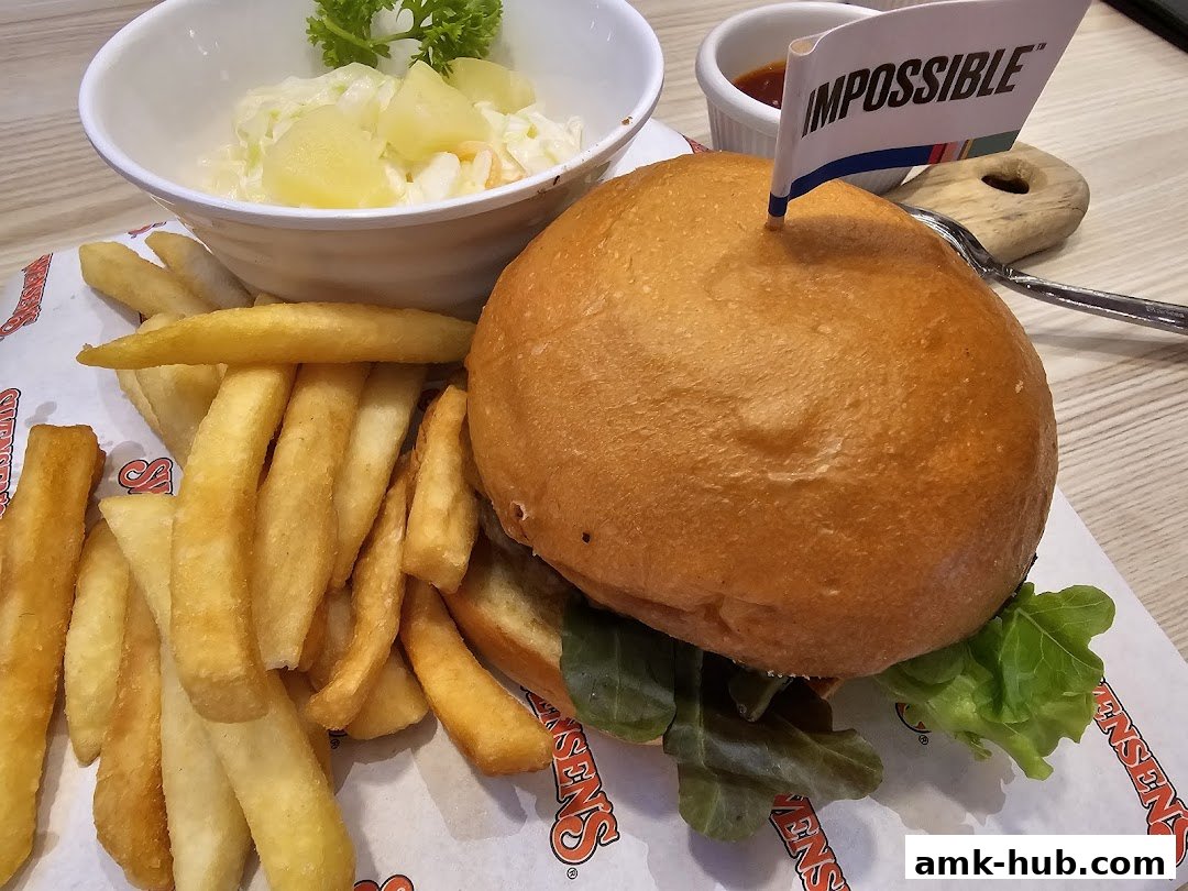 A delicious Impossible burger with fries and coleslaw, served on Swensen's branded paper.