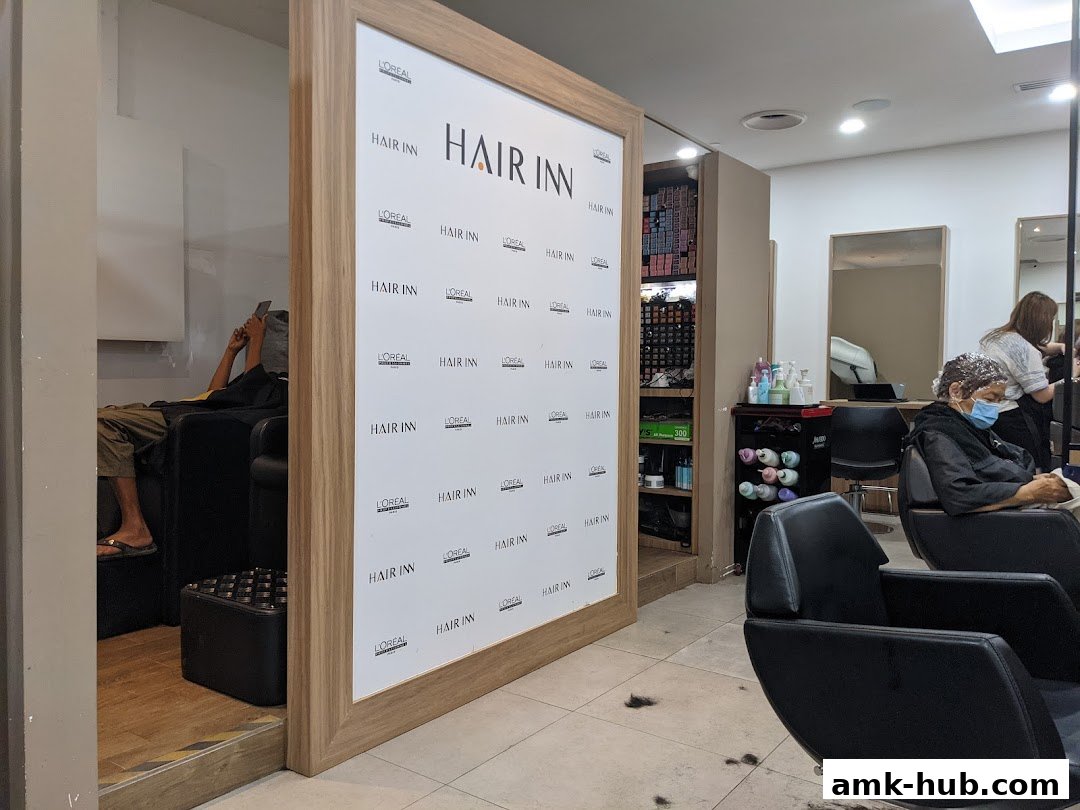 Interior of a hair salon with clients and staff, featuring L'Oreal branding.