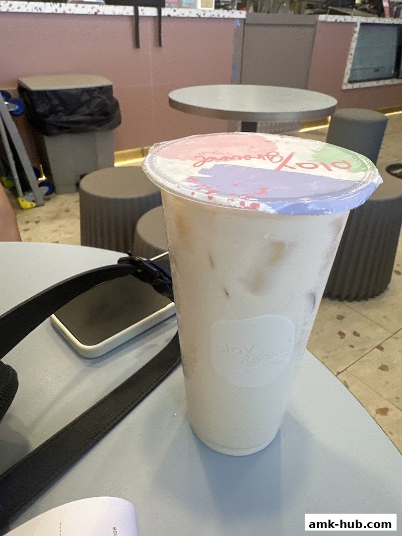 A refreshing beverage from Playground by PlayMade sits on a table with a phone and bag strap.