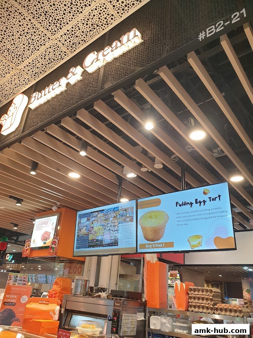 Butter & Cream bakery display with digital menus showcasing egg tarts and muffins.