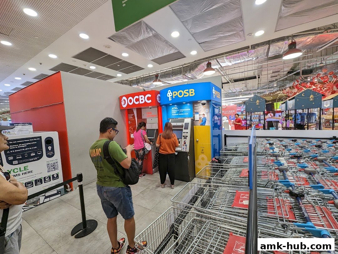 People using OCBC and POSB ATMs inside a retail store with shopping carts.