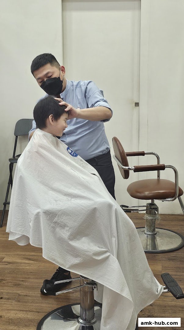 A barber is cutting a young boy's hair in a clean, modern salon.