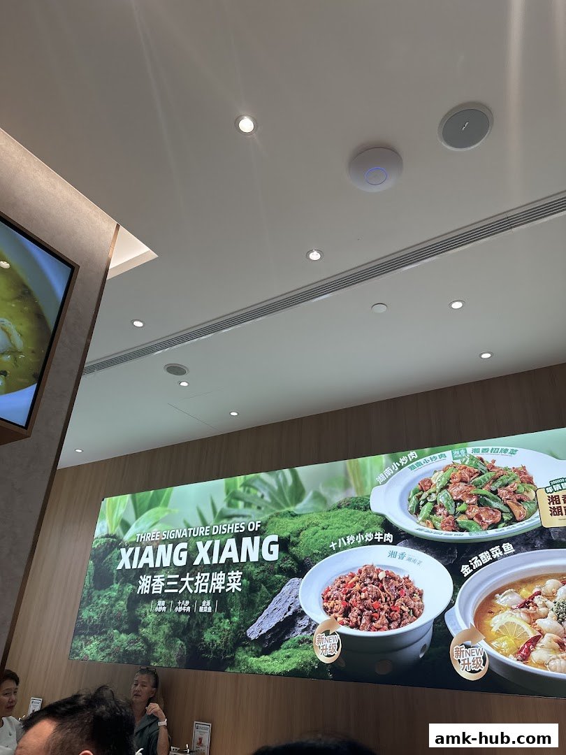 A large illuminated sign showcasing three signature dishes from Xiang Xiang Hunan Cuisine.