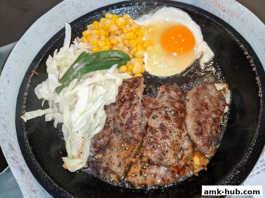 A sizzling hot plate of steak, egg, corn, and cabbage.