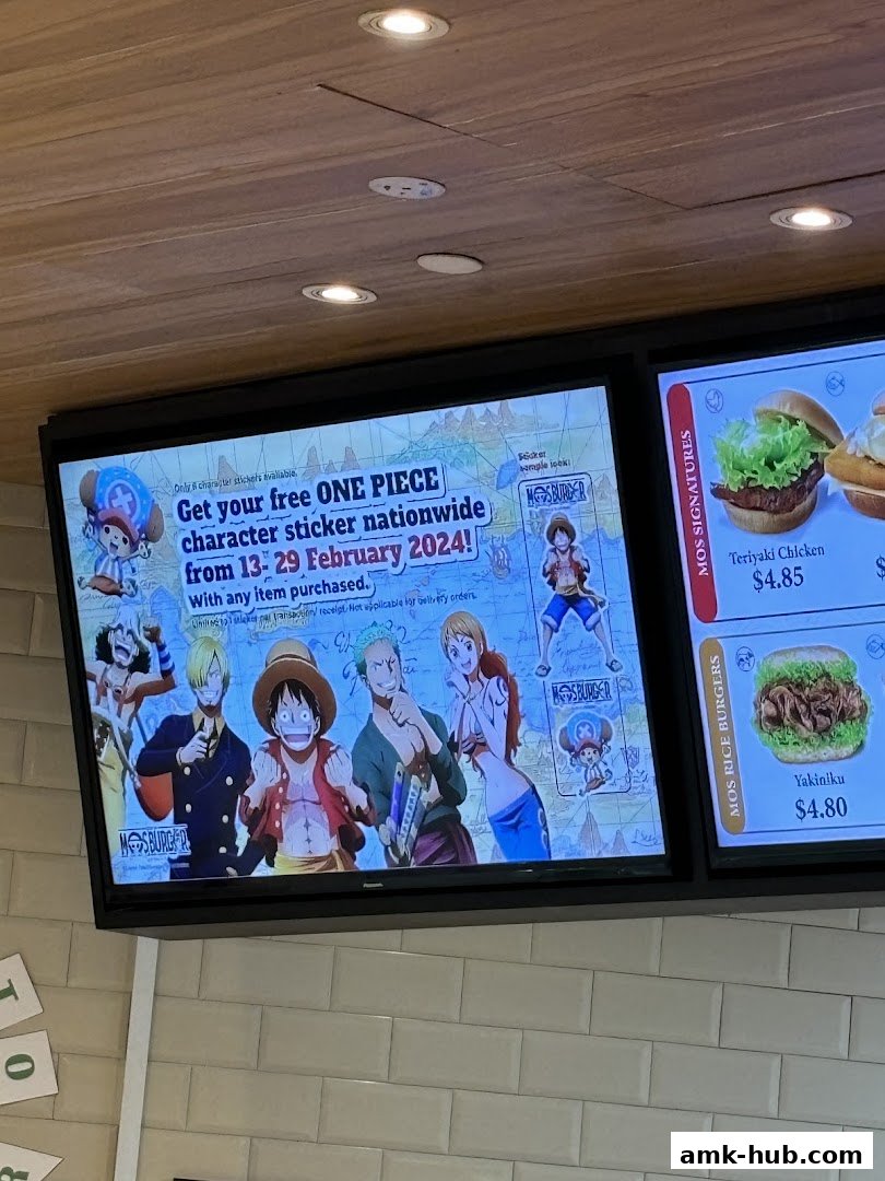 A digital display at MOS Burger promoting a One Piece sticker giveaway with item purchases.