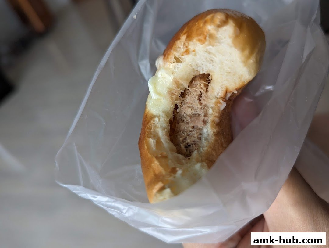 A close-up of a savory pastry with a filling, held in a plastic bag.