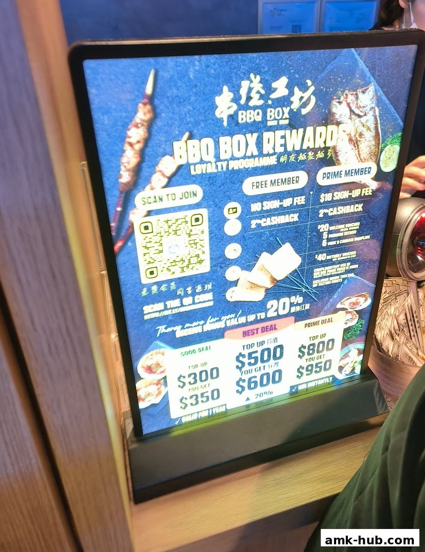 A digital display showing BBQ Box rewards program with membership tiers and top-up deals.
