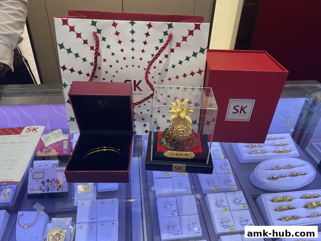 SK Jewellery display featuring a gold bracelet, pineapple ornament, and various rings in display cases.