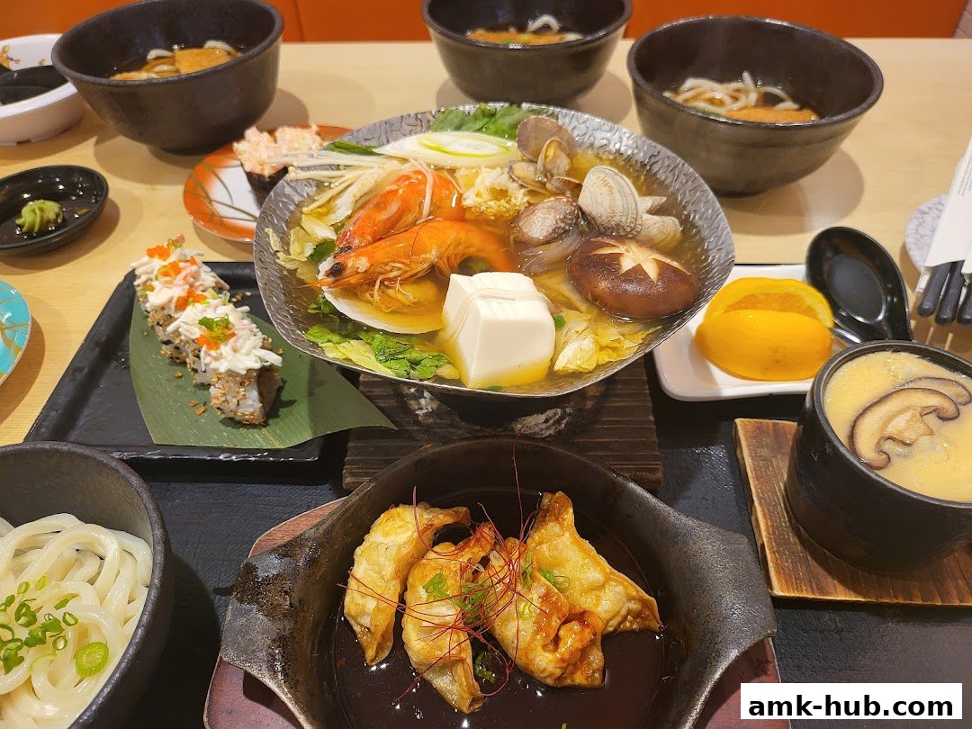 A table filled with various Japanese dishes including sushi, udon, and hot pot.