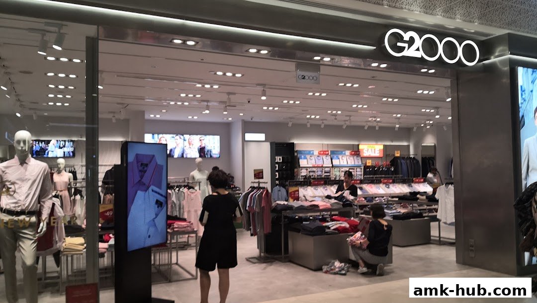 The G2000 shop front displays mannequins and racks of stylish clothing, with a digital screen showcasing shirts.