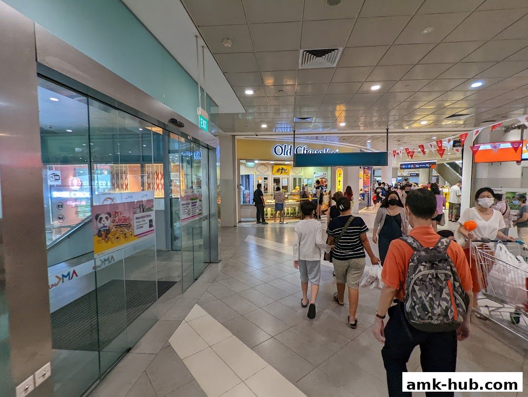 People walking in a mall hallway towards the Old Chang Kee shop.