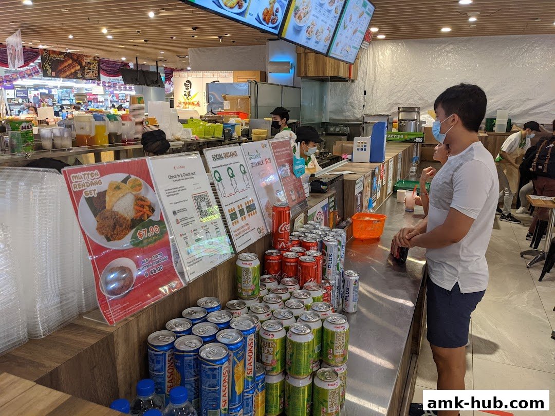 Customers ordering food at a counter with drinks and menu displays.