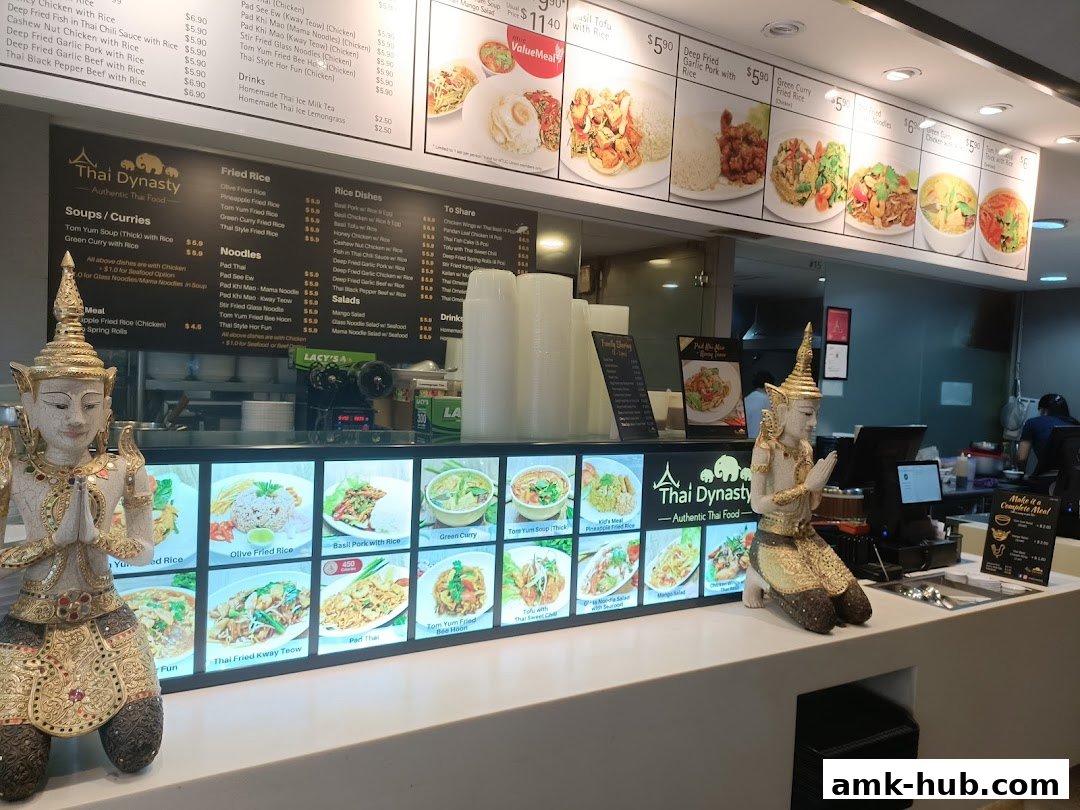 A Thai restaurant counter with a menu board, food displays, and decorative statues.