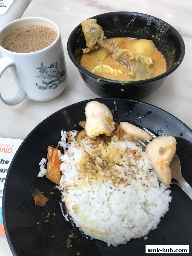 A close-up of a meal with rice, curry chicken, and a cup of coffee.