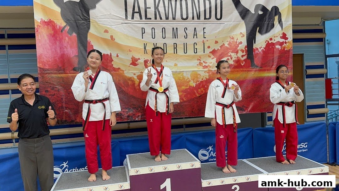 Taekwondo athletes on a podium receiving medals, with a coach giving a thumbs up.