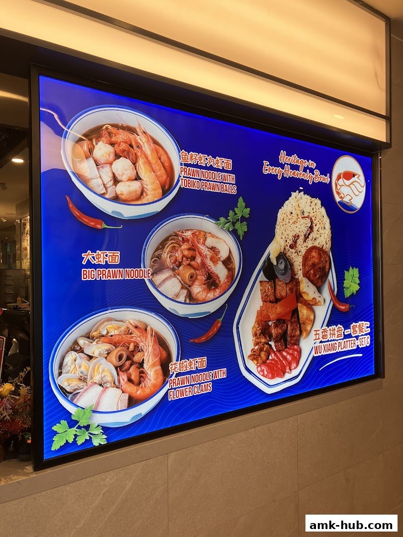 A brightly lit menu board showcasing three prawn noodle dishes and a platter.
