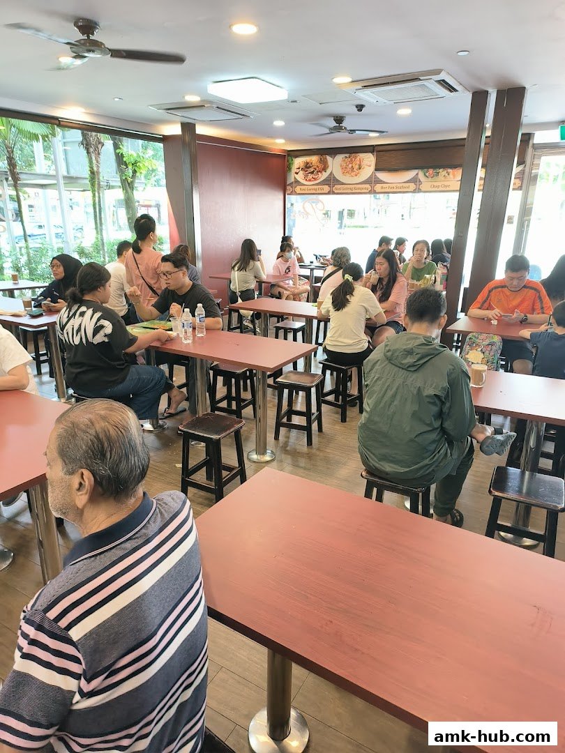 People dining at tables inside a restaurant with food pictures on the wall.