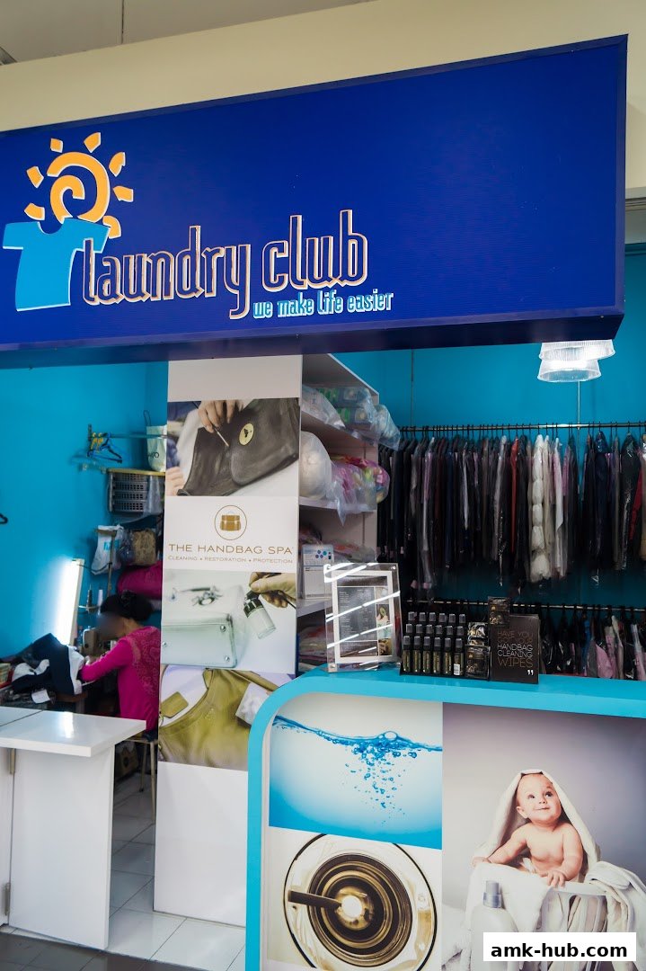 Interior view of a laundry service shop with clothes hanging and a person working.