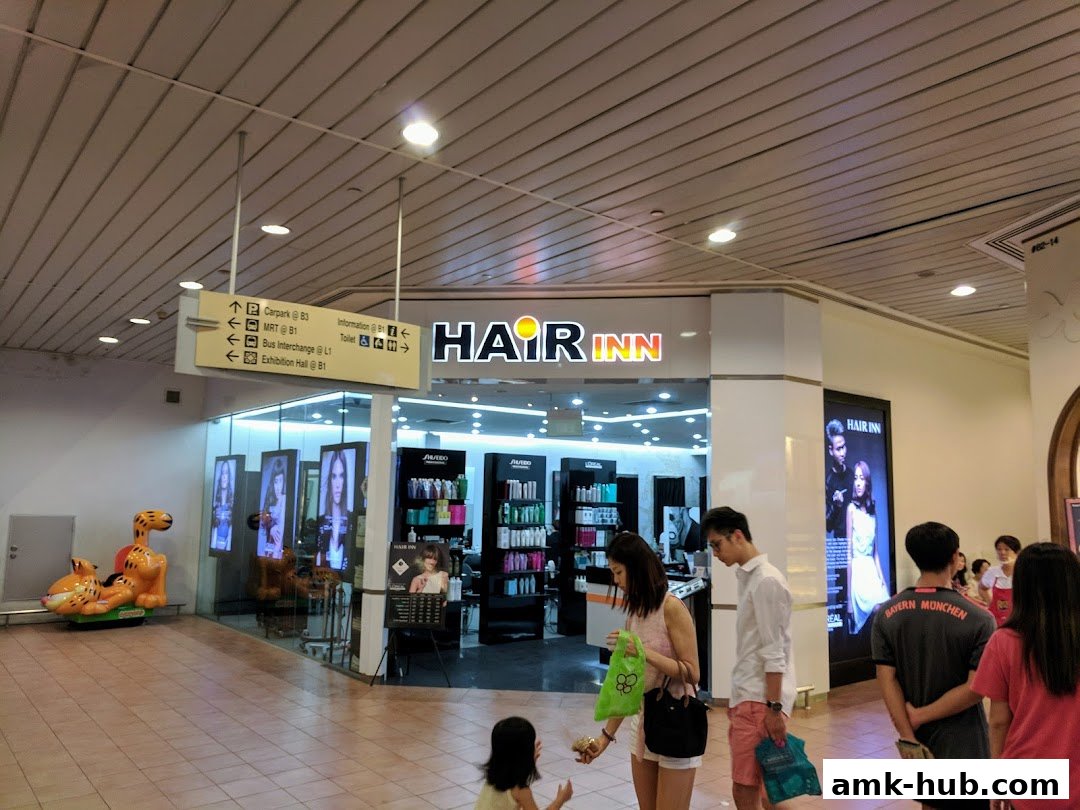 The Hair Inn salon entrance with products displayed and people walking by.