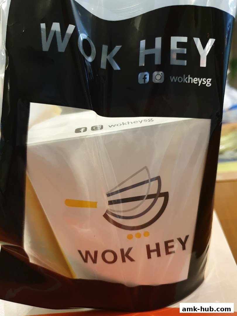 A Wok Hey takeaway bag with a branded food container inside.