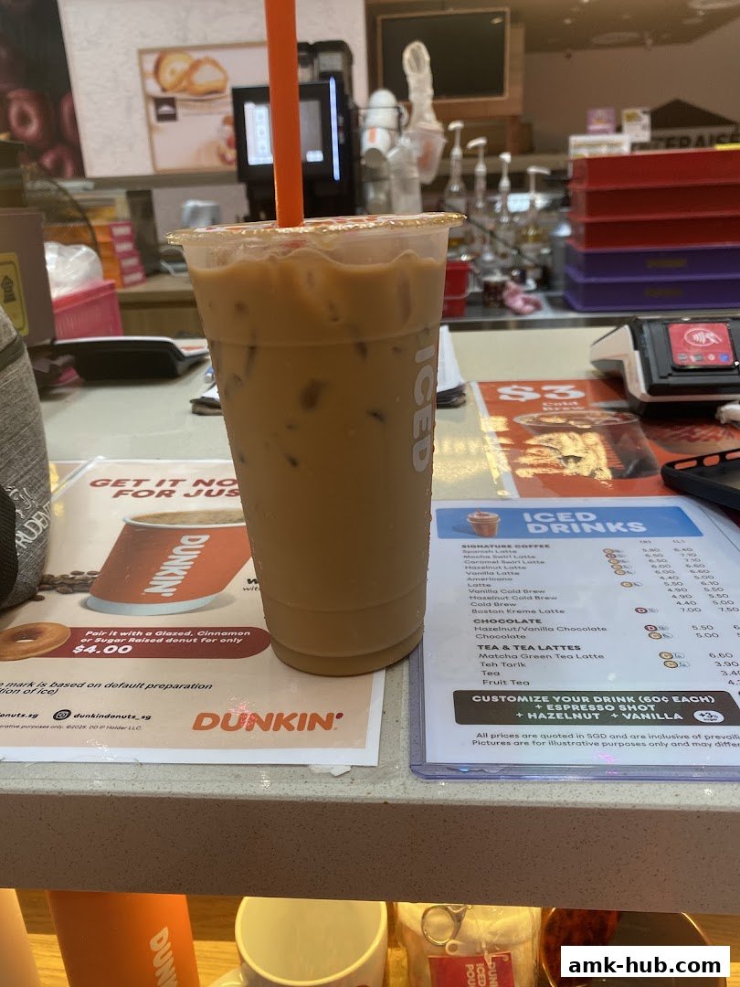 A close-up of an iced coffee drink next to a Dunkin' Donuts menu.