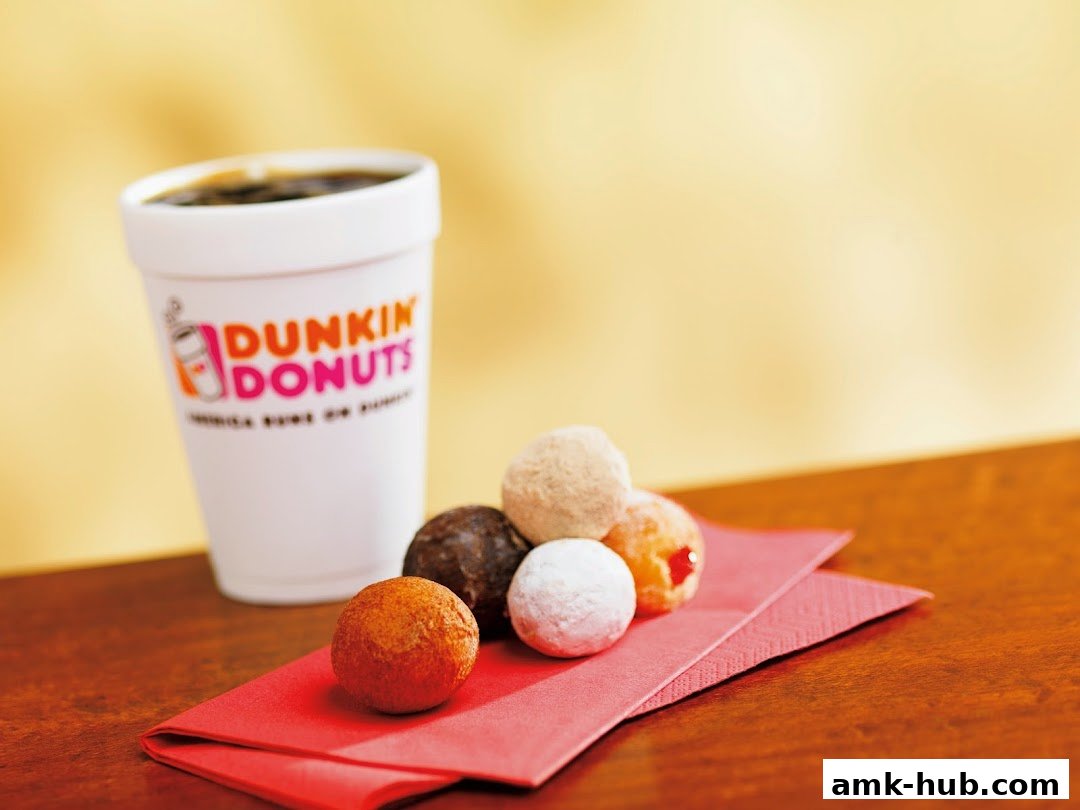 A cup of Dunkin' Donuts coffee sits next to a selection of colorful donut holes on a red napkin.