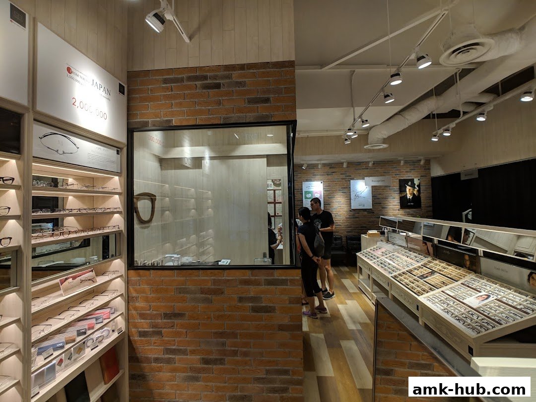Interior of an eyewear shop with shelves of glasses and customers browsing.