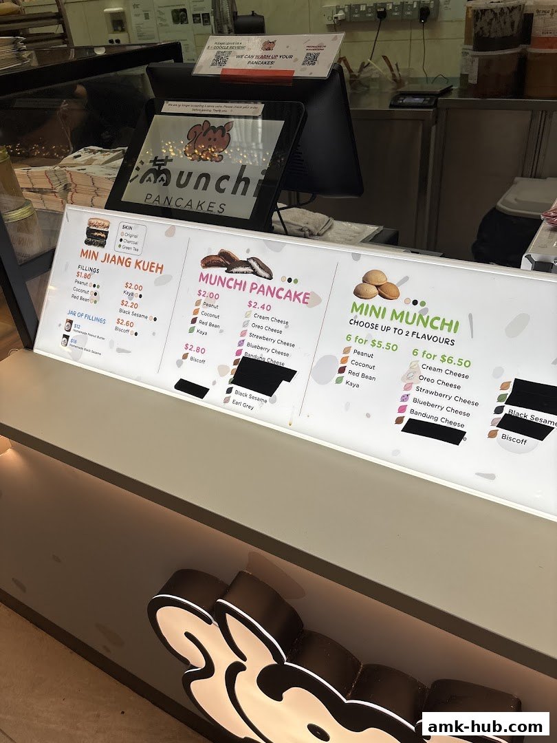 A brightly lit menu board for Munchi Pancakes, showcasing various pancake flavors and fillings.
