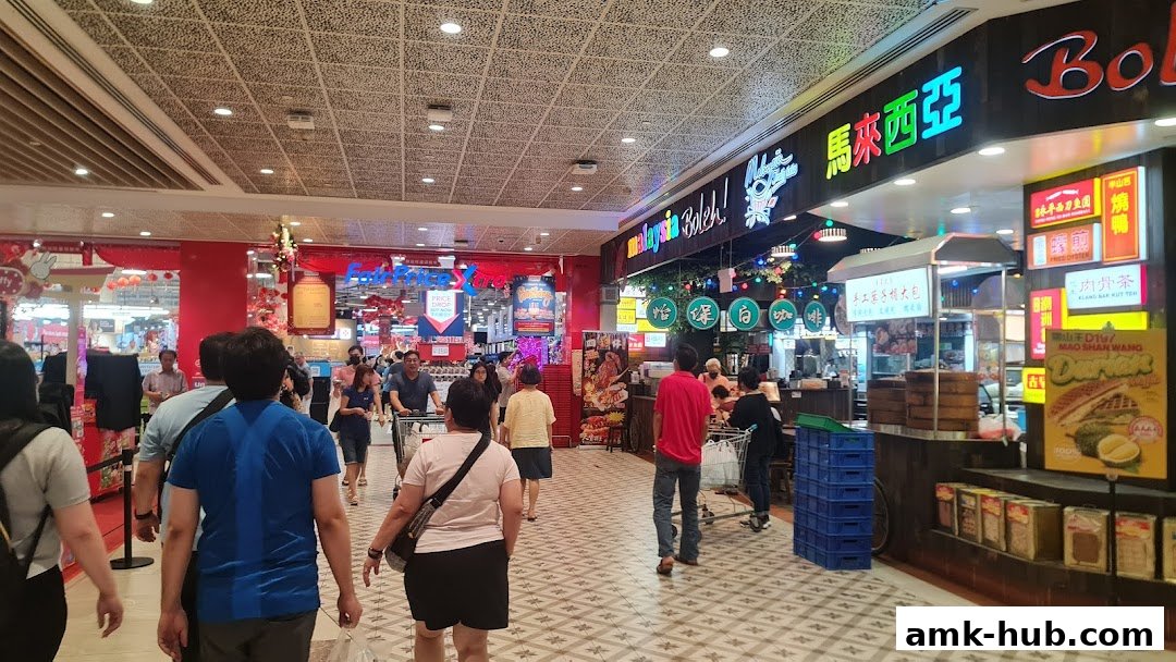People shopping inside a brightly lit supermarket with various food stalls.