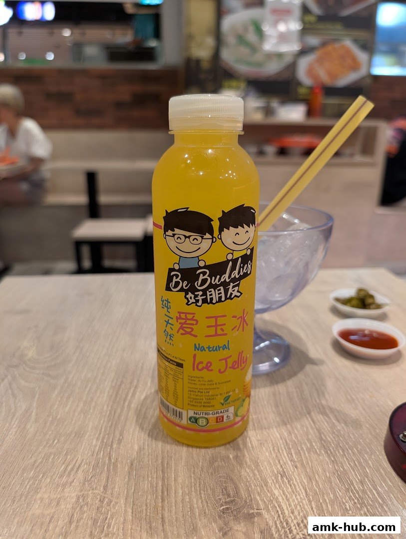 A bottle of Be Buddies Natural Ice Jelly drink on a wooden table with a straw and ice.