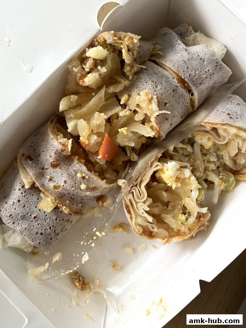 A close-up shot of sliced popiah in a white takeaway box.