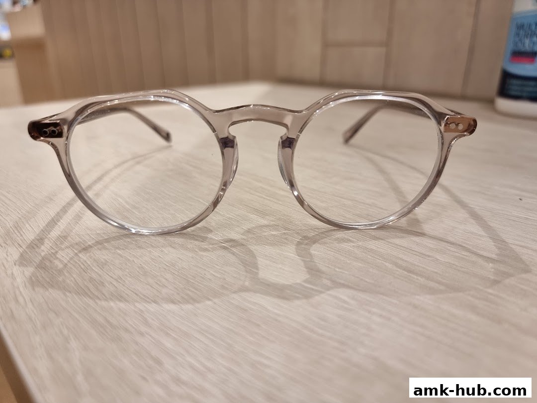A close-up shot of stylish, clear-rimmed eyeglasses resting on a wooden surface.