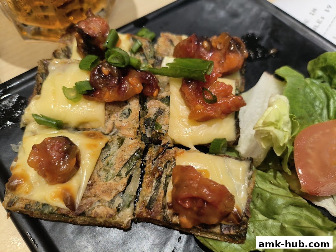 A close-up of a savory dish with melted cheese, meat, and green onions, served with a side salad.