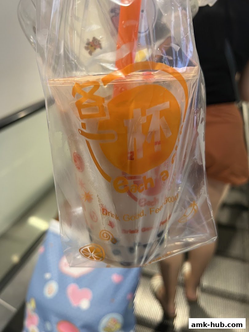 A person holds a bubble tea drink from Each A Cup in a plastic bag.
