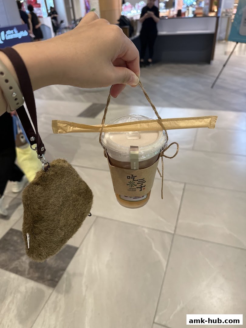A hand holds a takeaway drink from CHICHA San Chen with a furry pouch attached.