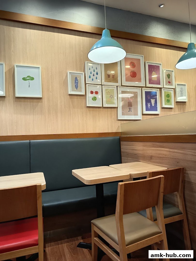 Interior shot of MOS Burger with booth seating, tables, chairs, and framed artwork on the wall.