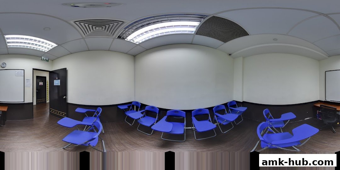 A classroom setting with blue chairs and desks, whiteboards, and an exit sign.