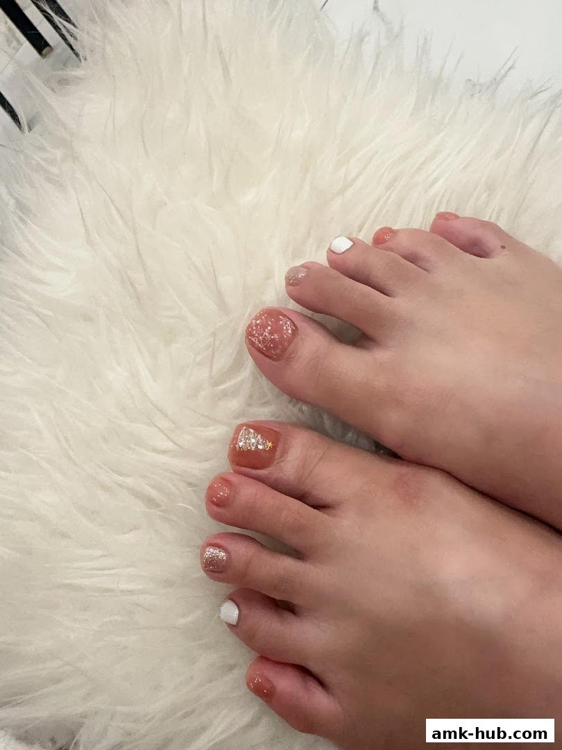 Close-up of feet with beautifully decorated toenails featuring glitter and festive designs.