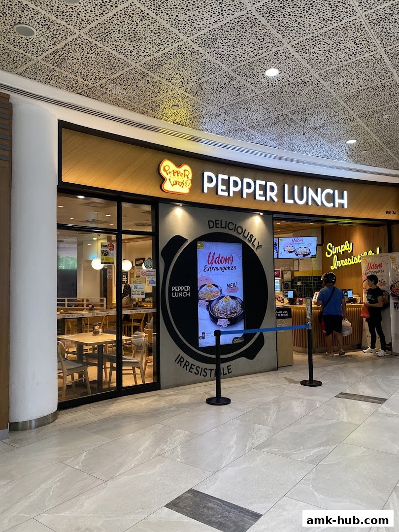 The exterior of a Pepper Lunch restaurant with its prominent signage and a digital display.