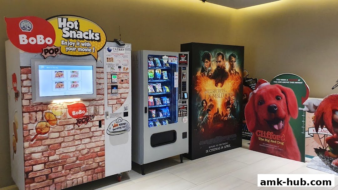Vending machines and movie posters at Cathay Cineplexes, offering snacks and promoting new films.